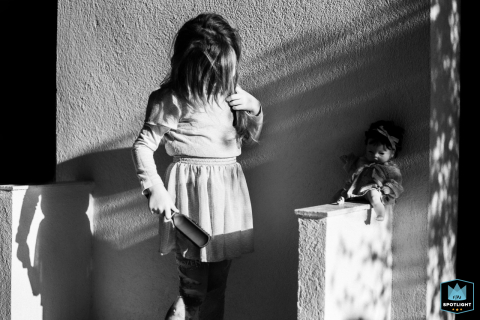 A candid black and white photograph captures a young girl brushing her hair during a hair styling session, taken by a Var family photographer.